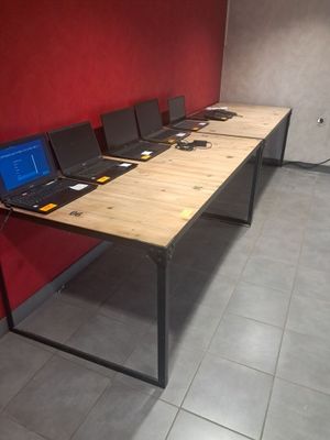 Plusieurs ordinateurs portables sont alignés sur une longue table dans une pièce
