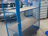 a large blue cage on the floor in a warehouse