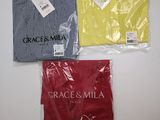 three shirts in plastic bags sitting on top of a table