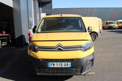une camionnette Citroën jaune garée devant un immeuble, sur un parking