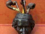 une statue d'homme avec des têtes de pipes dans un vase