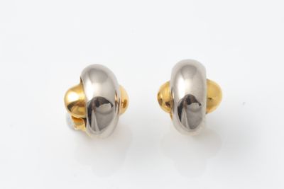 une paire de boucles d'oreilles en or et en argent posées sur une surface blanche