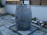 a black umbrella sitting on top of a wooden barrel