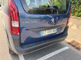 a blue van parked in a parking lot with trees in the background