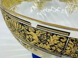 a gold and black bowl sitting on a blue stand