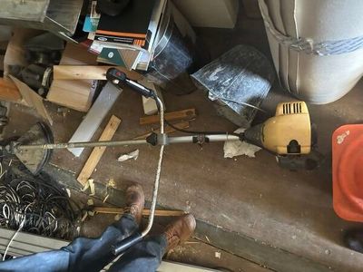 une photo d'un garage encombré avec des outils par terre