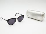 black sunglasses and a silver case on a white surface