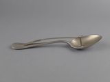 a close up of a silver spoon with a handle on a gray surface