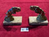 pair of bronze fish bookends on marble bases on a red background