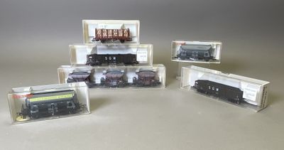 quatre modèles réduits de trains différents, présentés dans des boîtes transparentes posées sur une table