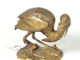 a bronze statue of a bird that is standing on a rock