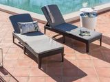 two lounge chairs and a table near a pool