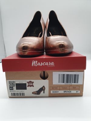 La boîte à chaussures est ouverte, laissant apparaître une paire de chaussures métalliques.