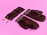 paire de mitaines en fourrure marron sur fond rose, ornées d'une chaîne dorée