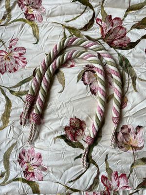a white and pink floral bed spread with a rope