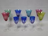 plusieurs verres à vin de couleurs différentes sont alignés sur une surface blanche