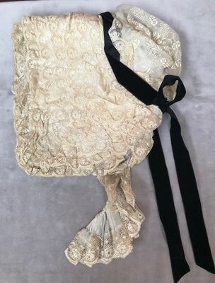 bonnet en dentelle couleur crème avec un ruban noir sur fond blanc