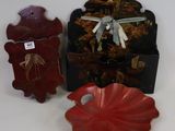 un pinceau rouge, un bol rouge et une boîte noire posés sur une surface blanche