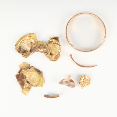une photo d'une bague en or et d'autres objets posés sur un fond blanc