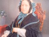 portrait of a woman sitting in a chair with a vase of flowers in the background