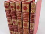 six livres rouges sont empilés les uns sur les autres sur une surface blanche