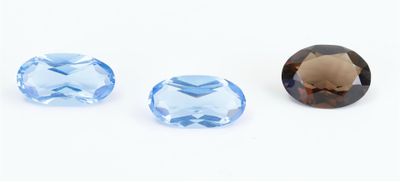 three different sizes of blue topazte stones on a white surface
