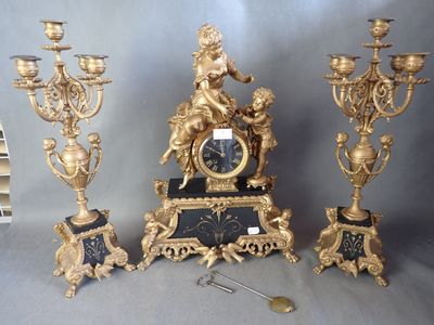 une horloge en or et un ensemble de trois bougeoirs