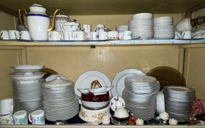 many plates and cups on a shelf in a cabinet