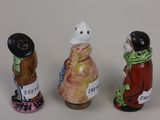 three small figurines of people are standing in a row