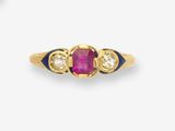un gros plan d'une bague en or sertie d'un rubis et de deux diamants blancs