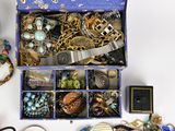 a blue box filled with assorted jewelry on a white surface
