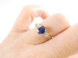 a woman ' s hand holding a ring with a blue stone on it