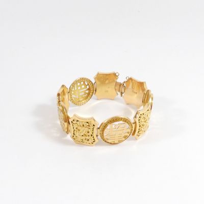 gros plan d'un bracelet en or sur une surface blanche