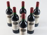 six bottles of wine are lined up in a row on a white surface