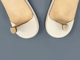 vue de dos d'une paire de chaussures blanches pour femme posées sur une surface bleue