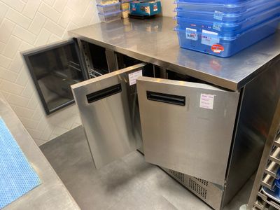 stainless steel counter top with blue bins on it in a commercial kitchen