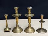 four brass candlesticks are sitting on a table with a black background