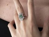 someone is wearing a ring that has a green stone on it