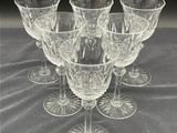 six clear wine glasses sitting on top of a table next to each other