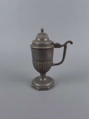 une théière ancienne en argent, avec couvercle et anse, posée sur un socle