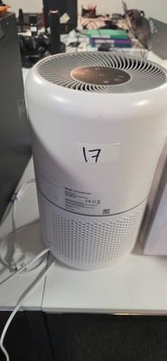 un purificateur d'air blanc posé sur un bureau, à côté d'un ordinateur portable
