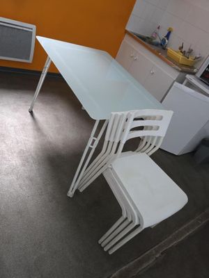 une table et des chaises blanches dans une petite pièce