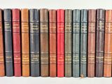 several old books are lined up in a row on a white surface