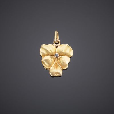 a yellow gold flower pendant with a diamond in the center