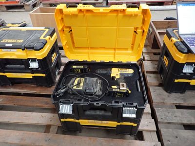 trois outils jaunes et noirs dans un coffret posé sur une palette