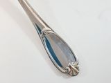 a silver spoon with a flower on it sitting on a table