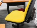 a yellow office chair sitting in front of a computer desk