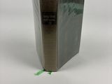 un livre ouvert posé sur une table blanche, à côté d'un ruban adhésif vert