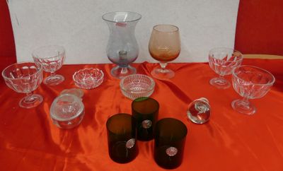 many glasses and vases on a table with a red table cloth