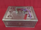 une petite boîte en métal ornée d'un ruban violet